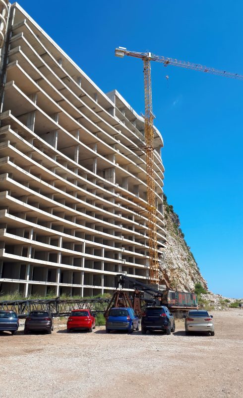 House construction with crane and parked cars in Petrovac, Montenegro