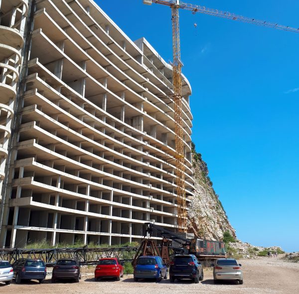 House construction in Petrovac, Montenegro House construction with crane and parked cars in Petrovac, Montenegro